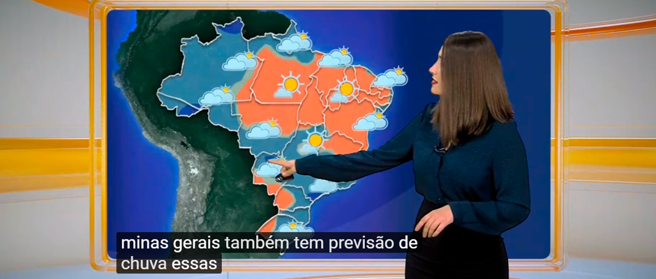 Foto colorida de uma apresentadora apontando uma região do mapa do Brasil. No mapa há diferentes regiões claras e escuras indicando as previsões de sol e chuva. Na parte inferior da foto está escrito em branco sobre duas tarjas pretas: 'Minas Gerais também tem previsão de chuva essas'. 