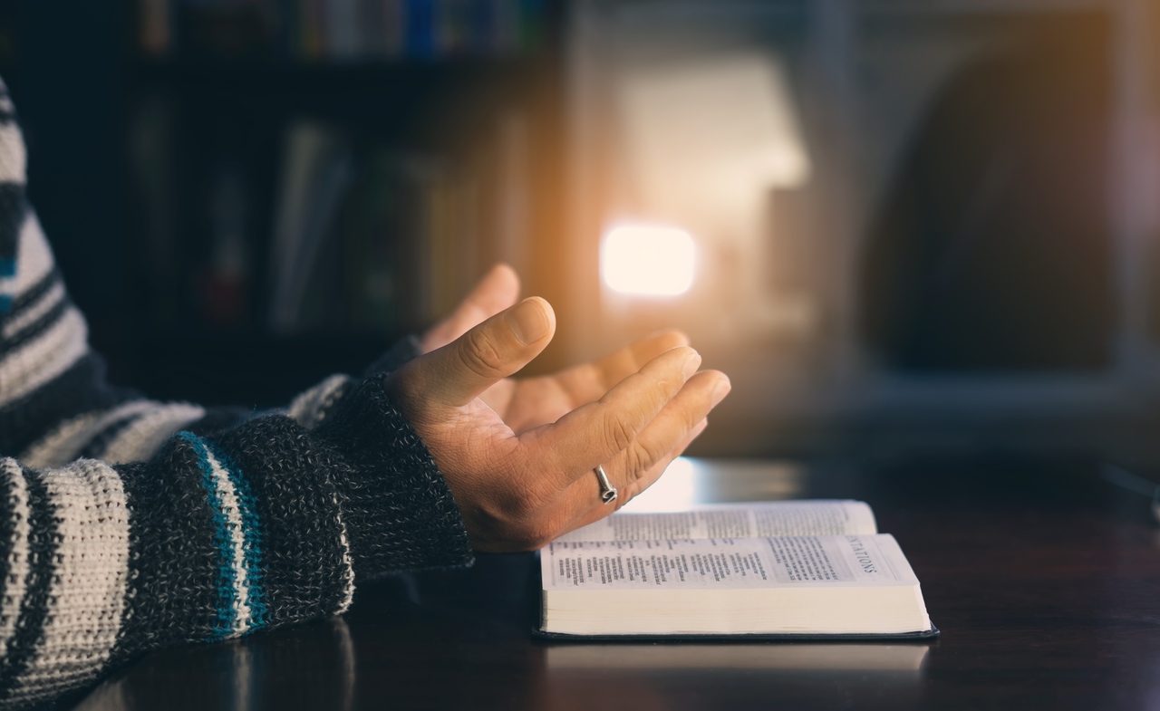 Руки во время молитвы. Мужчина молится над Библией.